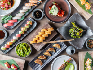 Full table spread of Nikkei cuisine featuring sushi rolls, gyoza, and appetizers at Paperfish Sushi, the best spot for group dining Brickell